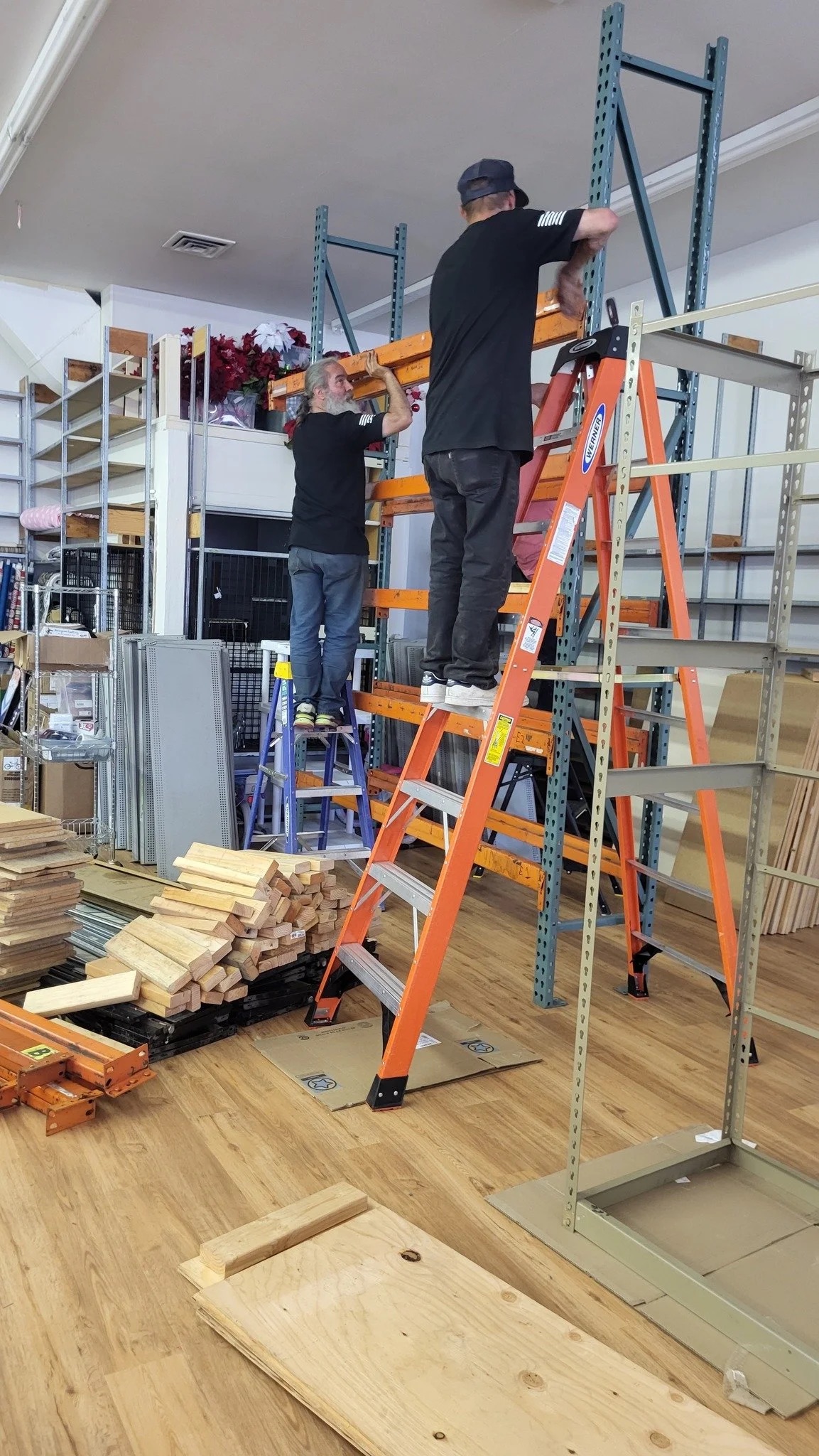 A volunteer on a ladder installing shelving