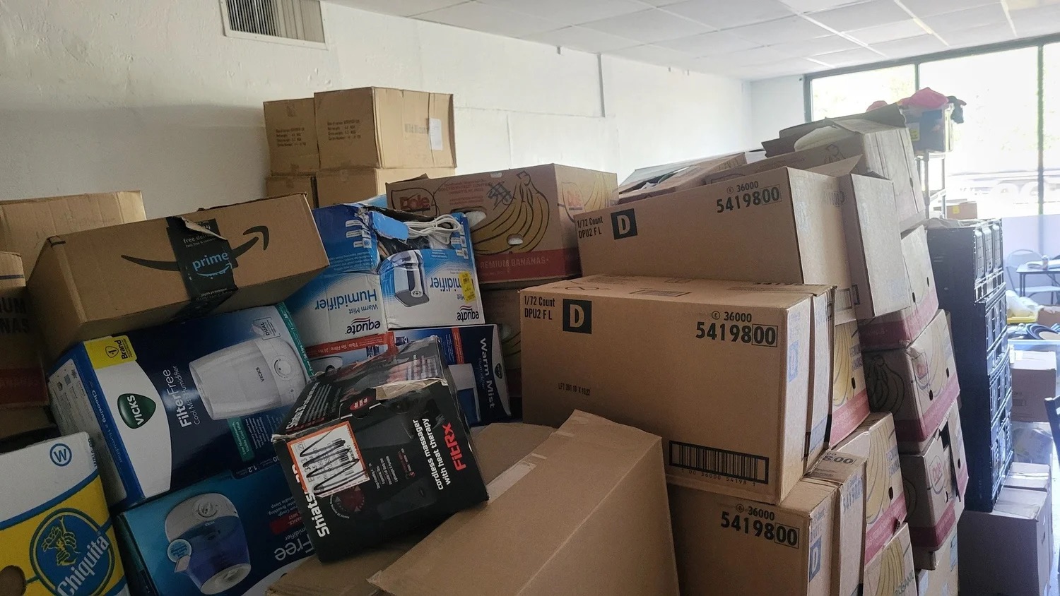 Donated goods stacked in boxes filling a storage room at Gg's House